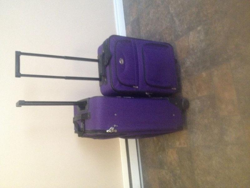 2 purple suitcases with pull handle and wheels