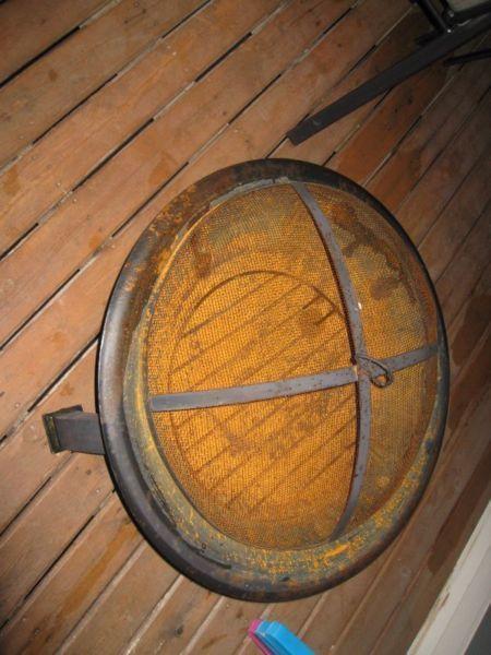 Rusted firepit with cooking grill and 2 boxes of wood